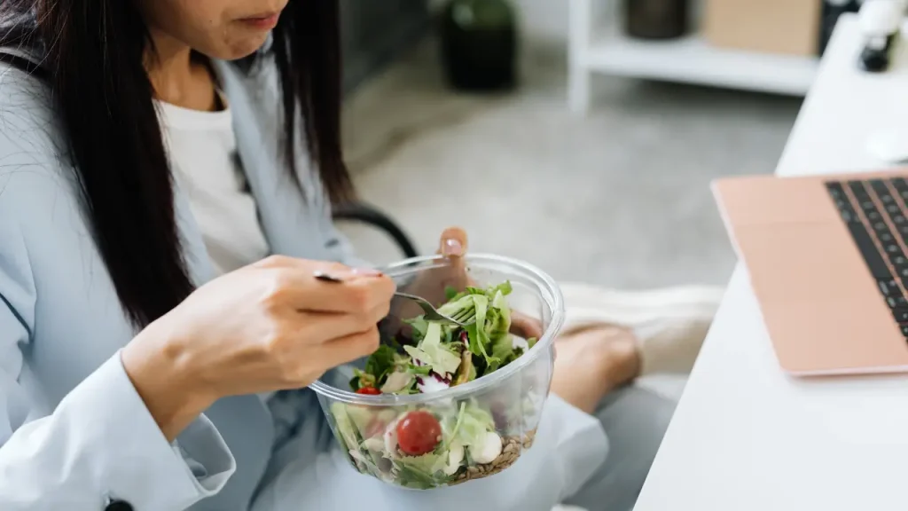 Colaborador comendo um pote de salada comprado com o cartão alimentação corporativo.